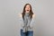 Crazy young woman in gray sweater, scarf screaming clenching fists like winner on grey background. Healthy