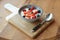 Cream and berries dessert in deep clay bowl on wooden board