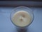 Cream candle in glass on window ledge