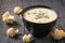 Cream cauliflower soup with chicken broth, cream and herbs on a black wooden table