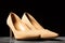 Cream-colored women's suede shoes with thin heels on a black background