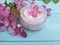 Cream cosmetic lotion ointment relaxation moisturizer protection glass essence magnolia handmade pink flowers on blue wooden
