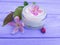 Cream cosmetic pink flowers on purple wooden wellness