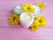 Cream cosmetic product yellow flowers pink wood background