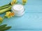 Cream cosmetic, yellow flowers blue wood background