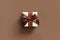 Cream gift box with a brown bow on a brown background