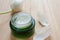 Cream in green glass jar on wooden background