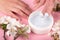 Cream on the hand close-up, white scrub on a pink background with white flowers of apple,skin care,beauty, moisturizing cosmetics