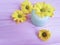 Cream jar cosmetic product yellow chamomile flowers pink wood background