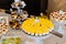 Cream slices with yellow glaze on a round presentation plate with label for labeling, surrounded by pastries