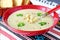 Cream of Vegetable with Cauliflower and cream in a red ceramic bowl on a textile background. Healthy eating concept.