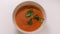 Creamy bowl of tomato soup with fresh coriander leaves