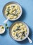 Creamy cheesy spinach potato gnocchi on a blue background, top view. Mediterranean food