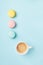 Creamy coffee and colorful macaron on pastel blue background top view. Cozy morning breakfast. Fashion flat lay. Sweet macaroons.