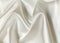 Creamy crumpled or wavy fabric texture background. Abstract linen cloth soft waves. Creases of satin, silk, and cotton