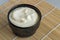 Creamy fruit yogurt in black bowl on reed table mat close up
