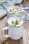 Creamy potato soup garnished with bacon and green onion, served in mug