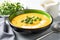 Creamy pumpkin fall soup in green bowl on the light gray table. Butternut squash cream soup garnished with heavy cream