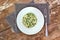 Creamy risotto with peas and spinach on white plate on grey cloth on rustic table