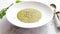 Creamy soup with green pea in a ceramic white plate