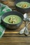 Creamy spinach soup with crackers, herbs and chia seeds. Green soup served in a bowl on a wooden table