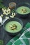 Creamy spinach soup with crackers, herbs and chia seeds. Green soup served in a bowl on a wooden table. Flat lay