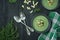 Creamy spinach soup with crackers, herbs and chia seeds. Green soup served in a bowl on a wooden table. Space for text. Flat lay