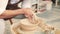 Creating vase of beige clay close-up. The sculptor in workshop makes jug out of clay closeup. Twisted potter`s wheel