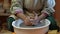 Creating vase of white clay close-up. The sculptor in workshop makes jug out of clay closeup. Twisted potter`s wheel.