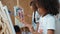 Creative african girl painted or draw canvas together with asian boy. Erudition.
