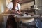 Creative artisan measuring a turning vase in her workshop