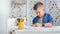 Creative attractive male child drawing colorful picture paper enjoying art at home