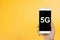 Creative background, hand holding a phone with a symbol 5G. The concept of 5G network, high-speed mobile Internet, new