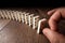 Creative background, Male hand pushing white dominoes, on a brown wooden background. Concept of domino effect, chain