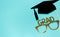 Creative background with photobooth props for graduation: hats, diploma, glasses, lips on bright blue paper background. Education