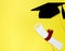 Creative background with photobooth props for graduation: hats, diploma, glasses, lips on bright yellow paper background.