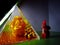 Creative background of the pyramid and the little cartoon statuette