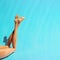 Creative beach concept, doll legs on blue background with shadows, sunbathing; Minimal summer vacation concept with copy space