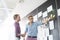 Creative businessmen discussing over sticky paper on wall in office