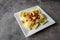 Creative cheese ravioli topped with fresh tomato and avocado and seasoning.