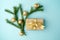Creative Chistmas layout made of winter greenery, kraft gift box with golden ribbon and golden decoration on blue background