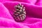 Creative Christmas background made with fir cone and soft magenta knitting. Minimal composition. Cozy and warm New Year