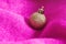 Creative Christmas background made with shiny golden ball ornament and soft magenta knitting. Minimal composition. Cozy