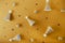 Creative Christmas background in trendy golden color. Festive paper shining caps, small balls and stars on a warm yellow