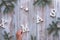 Creative Christmas flat lay on rustic wooden boards. Hand holding letter in word Xmas. Fir twigs decorated with snowflakes and