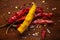 Creative close-up composition of red Chili pepper and dry yellow turmeric root on brown wooden top