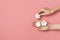 Creative composition with cotton. Hands of young woman holding white cotton flowers on pink background. Top view flat lay copy