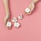 Creative composition with cotton. Hands of young woman holding white cotton flowers on pink background. Top view flat lay copy