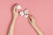 Creative composition with cotton. Hands of young woman holding white cotton flowers on pink background. Top view flat lay copy