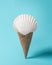 Creative composition with seashell and ice cream cone on pastel blue background. Summer minimal concept
